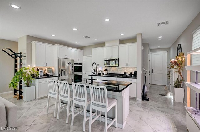 4160 Elegant Chateau St, Las Vegas, NV 89135 - kitchen featuring appliances with stainless steel finishes, a sink, dark countertops, tasteful backsplash, and a kitchen breakfast bar