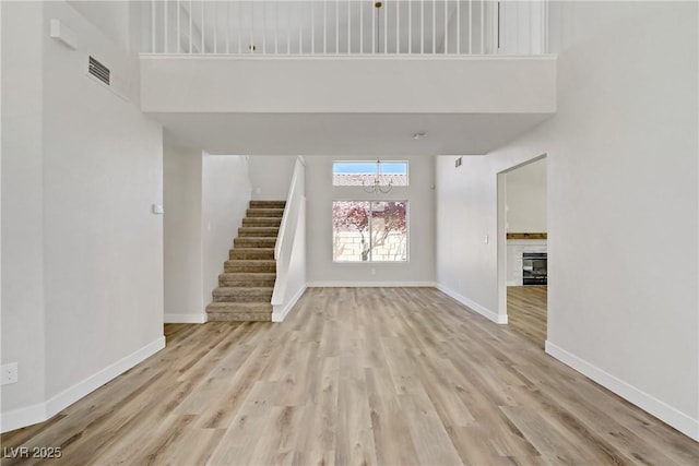 7813 Paper Flower Ct, Las Vegas, NV 89128 - unfurnished living room featuring a high ceiling, a chandelier, stairway, a tiled fireplace, and wood finished floors