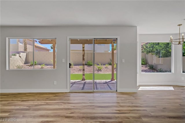 7813 Paper Flower Ct, Las Vegas, NV 89128 - empty room with wood finished floors, a chandelier, baseboards, and healthy amount of natural light
