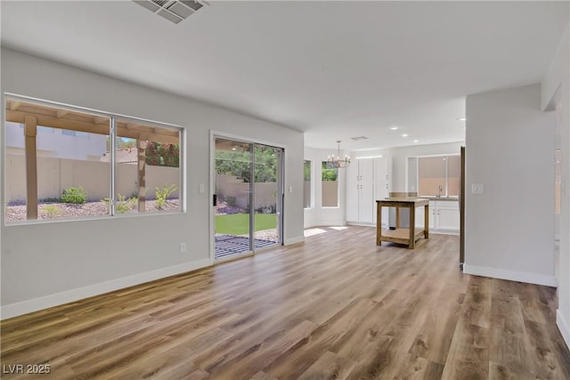 7813 Paper Flower Ct, Las Vegas, NV 89128 - unfurnished living room with a chandelier, baseboards, wood finished floors, recessed lighting, and a sink
