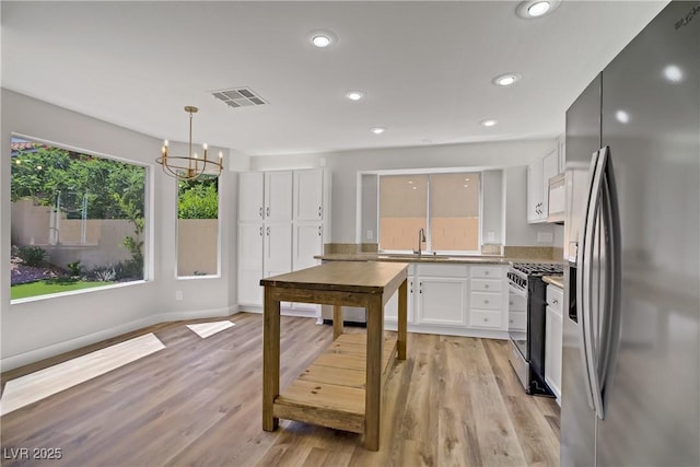 7813 Paper Flower Ct, Las Vegas, NV 89128 - kitchen with appliances with stainless steel finishes, white cabinetry, a chandelier, light wood-type flooring, and recessed lighting