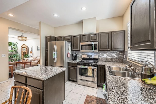 310 Pissarro Pl, Henderson, NV 89074 - kitchen with appliances with stainless steel finishes, a sink, tasteful backsplash, light tile patterned floors, and a center island