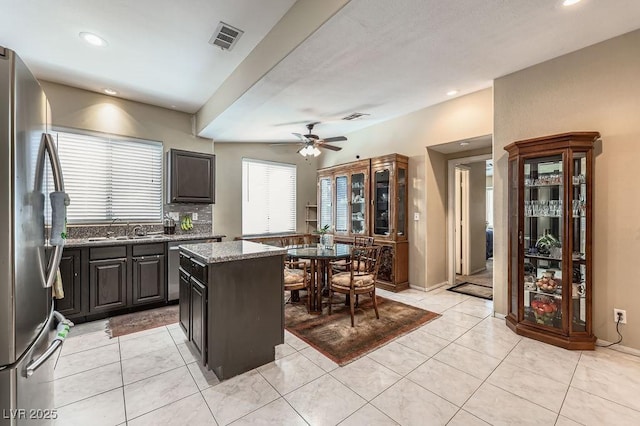310 Pissarro Pl, Henderson, NV 89074 - kitchen with freestanding refrigerator, a sink, stone countertops, ceiling fan, and light tile patterned flooring