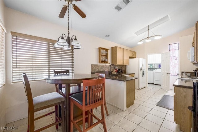 3121 Fontana Colony Ct, North Las Vegas, NV 89031 - kitchen with separate washer and dryer, white appliances, dark countertops, lofted ceiling, and a peninsula