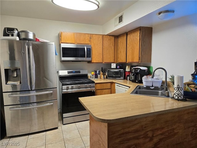 4612 Supreme Ct, Las Vegas, NV 89110 - kitchen featuring stainless steel appliances, a sink, light tile patterned floors, a peninsula, and brown cabinets