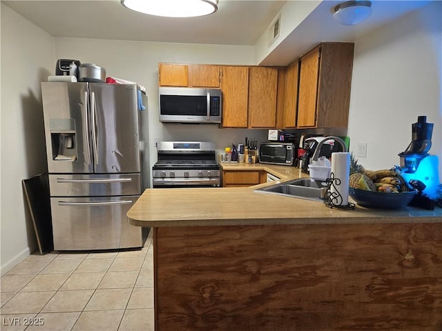 4612 Supreme Ct, Las Vegas, NV 89110 - kitchen with appliances with stainless steel finishes, a sink, brown cabinets, light tile patterned floors, and a peninsula