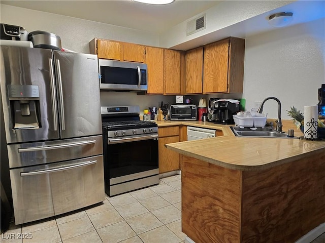 4612 Supreme Ct, Las Vegas, NV 89110 - kitchen with stainless steel appliances, a sink, a peninsula, brown cabinets, and light countertops