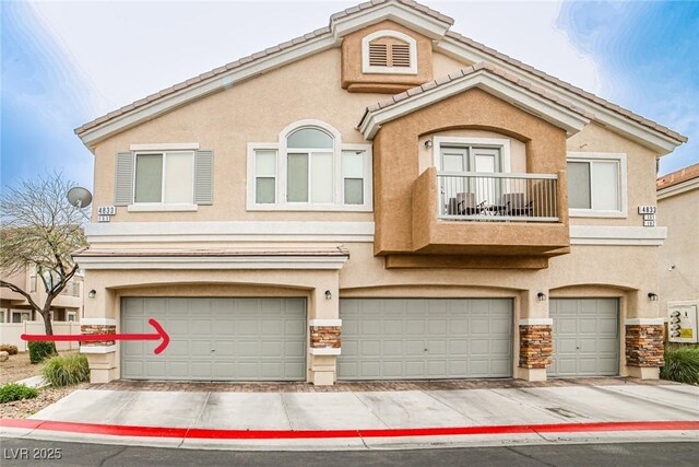4833 Straight Flush Dr Unit 103, Las Vegas, NV 89122 - view of property featuring a garage, stucco siding, stone siding, and a balcony