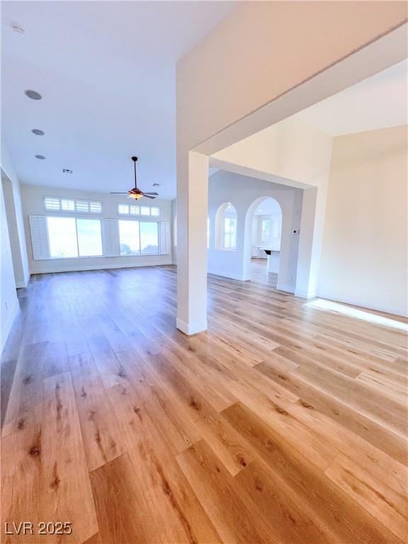 8616 Willow Cabin St, Las Vegas, NV 89131 - unfurnished living room featuring light wood-type flooring, healthy amount of natural light, a ceiling fan, and arched walkways