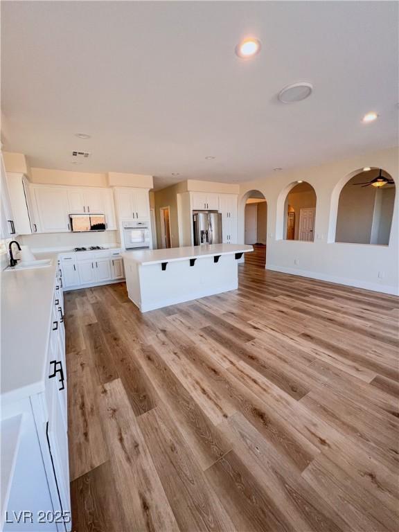 8616 Willow Cabin St, Las Vegas, NV 89131 - kitchen with stainless steel fridge, oven, a breakfast bar, a sink, and white cabinets