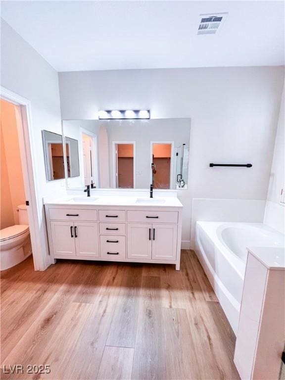 8616 Willow Cabin St, Las Vegas, NV 89131 - full bathroom featuring double vanity, a garden tub, toilet, and wood finished floors