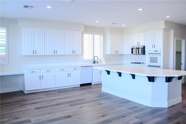 8616 Willow Cabin St, Las Vegas, NV 89131 - kitchen with white dishwasher, white cabinets, a kitchen island, a kitchen bar, and recessed lighting
