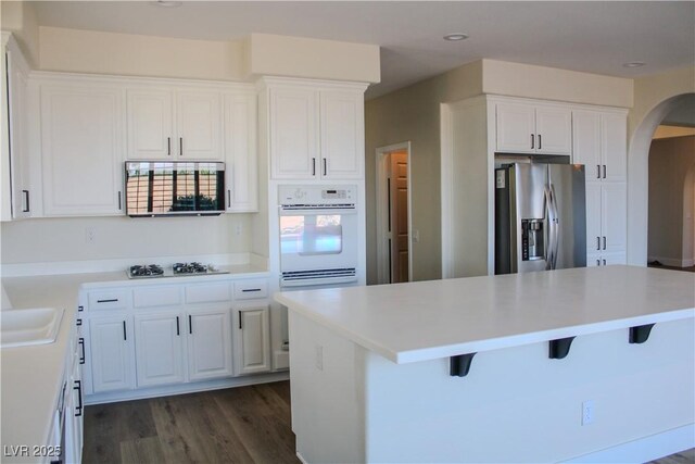 8616 Willow Cabin St, Las Vegas, NV 89131 - kitchen with oven, stainless steel fridge, arched walkways, white cabinets, and a breakfast bar area
