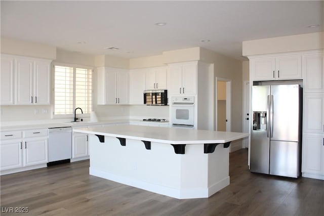8616 Willow Cabin St, Las Vegas, NV 89131 - kitchen featuring white appliances, a kitchen island, white cabinets, dark wood-type flooring, and a sink