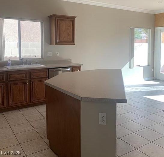 6412 Starling Mesa St, North Las Vegas, NV 89086 - kitchen featuring a sink, light tile patterned floors, a kitchen island, healthy amount of natural light, and crown molding
