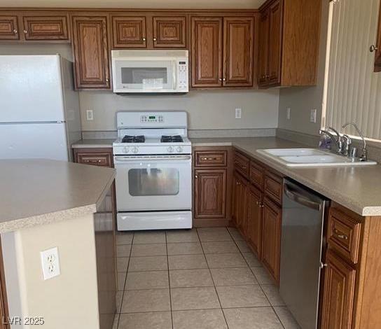 6412 Starling Mesa St, North Las Vegas, NV 89086 - kitchen with white appliances, a sink, light tile patterned flooring, brown cabinetry, and light countertops