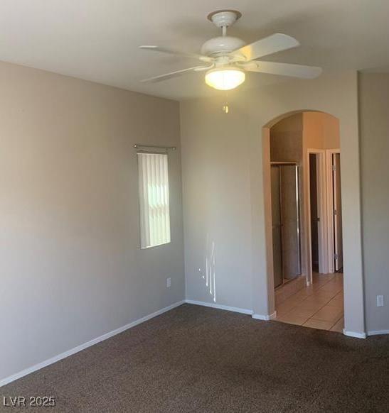 6412 Starling Mesa St, North Las Vegas, NV 89086 - tiled spare room featuring a ceiling fan, carpet floors, arched walkways, and baseboards