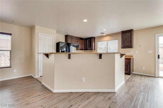 8745 Dodds Canyon St, Las Vegas, NV 89131 - kitchen featuring black fridge, a kitchen bar, light wood finished floors, dark brown cabinets, and recessed lighting