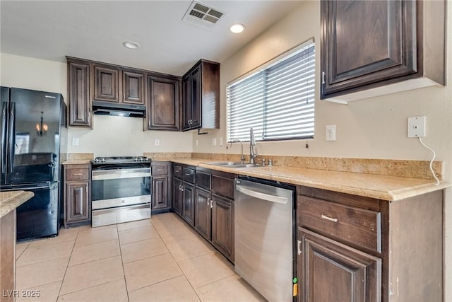 8745 Dodds Canyon St, Las Vegas, NV 89131 - kitchen with stainless steel appliances, under cabinet range hood, light tile patterned floors, dark brown cabinetry, and light countertops