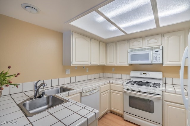 5713 Whiteridge Ave, Las Vegas, NV 89107 - kitchen with white appliances, a sink, tile counters, and light wood finished floors