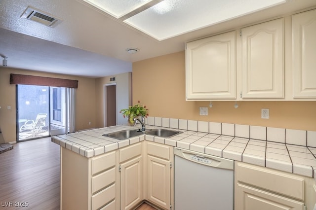 5713 Whiteridge Ave, Las Vegas, NV 89107 - kitchen with white dishwasher, a sink, tile counters, light wood-type flooring, and a peninsula
