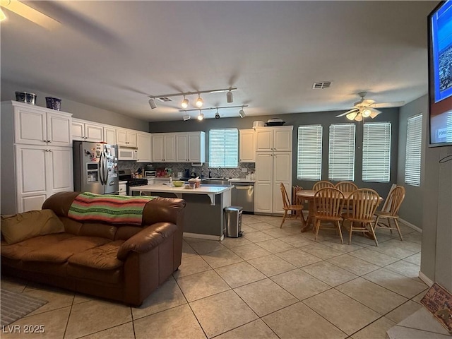 2267 Muir Ct, Henderson, NV 89052 - kitchen with appliances with stainless steel finishes, ceiling fan, light tile patterned floors, white cabinetry, and backsplash