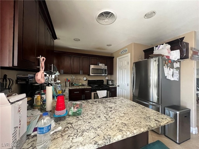 1429 S Sandhill Rd, Las Vegas, NV 89104 - kitchen featuring stainless steel appliances, a peninsula, dark brown cabinetry, light stone counters, and light tile patterned flooring