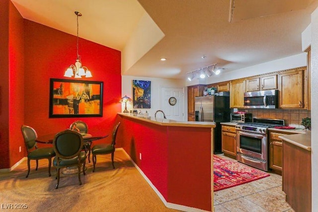8777 Maule Ave Unit 3116, Las Vegas, NV 89148 - kitchen with appliances with stainless steel finishes, a peninsula, hanging light fixtures, decorative backsplash, and a chandelier