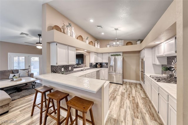 7670 Descanso Ln, Las Vegas, NV 89123 - kitchen featuring appliances with stainless steel finishes, a peninsula, a breakfast bar area, ceiling fan, and tasteful backsplash
