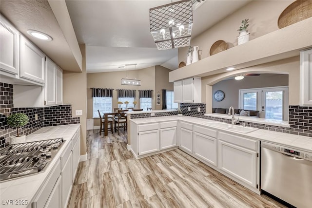7670 Descanso Ln, Las Vegas, NV 89123 - kitchen with stainless steel dishwasher, decorative backsplash, tile countertops, lofted ceiling, and white cabinetry