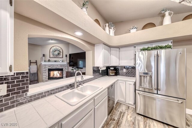 7670 Descanso Ln, Las Vegas, NV 89123 - kitchen featuring appliances with stainless steel finishes, tile counters, white cabinetry, tasteful backsplash, and light wood-style flooring