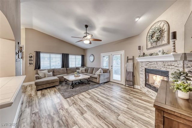 7670 Descanso Ln, Las Vegas, NV 89123 - living area featuring vaulted ceiling, a ceiling fan, light wood finished floors, a stone fireplace, and arched walkways