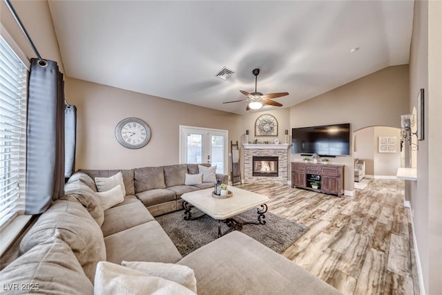 7670 Descanso Ln, Las Vegas, NV 89123 - living room featuring ceiling fan, lofted ceiling, wood finished floors, arched walkways, and a glass covered fireplace