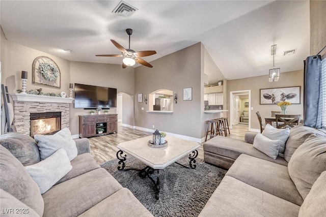 7670 Descanso Ln, Las Vegas, NV 89123 - living room with a stone fireplace, lofted ceiling, ceiling fan, light wood-style floors, and arched walkways