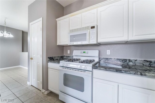 9303 Gilcrease Ave Unit 1013, Las Vegas, NV 89149 - kitchen with white appliances, a chandelier, white cabinets, dark stone counters, and light tile patterned floors