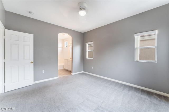 9303 Gilcrease Ave Unit 1013, Las Vegas, NV 89149 - unfurnished bedroom with light carpet, arched walkways, baseboards, connected bathroom, and a ceiling fan
