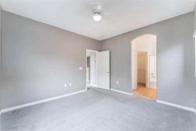 9303 Gilcrease Ave Unit 1013, Las Vegas, NV 89149 - unfurnished bedroom with arched walkways, light carpet, baseboards, connected bathroom, and a ceiling fan