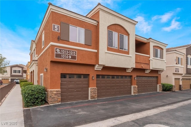 9303 Gilcrease Ave Unit 1013, Las Vegas, NV 89149 - view of front facade with stone siding, a garage, stucco siding, and driveway
