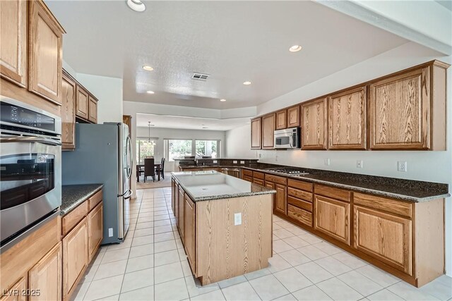 7465 Widewing Dr, North Las Vegas, NV 89084 - kitchen with stainless steel appliances, recessed lighting, a peninsula, a center island, and dark stone countertops