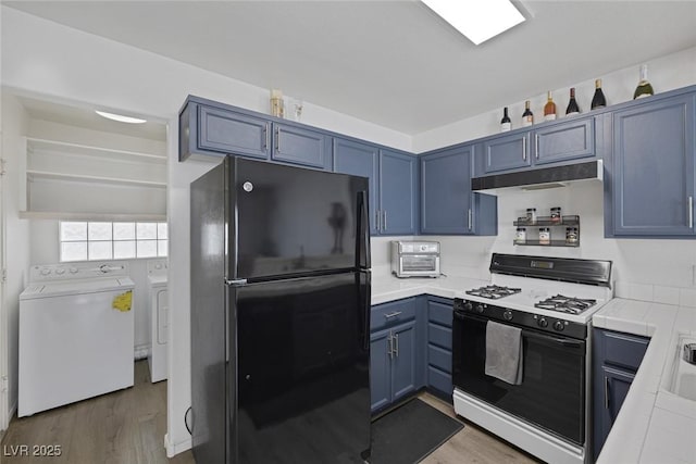 3481 Creek River Dr, Las Vegas, NV 89129 - kitchen with washing machine and dryer, freestanding refrigerator, gas stove, wood finished floors, and under cabinet range hood