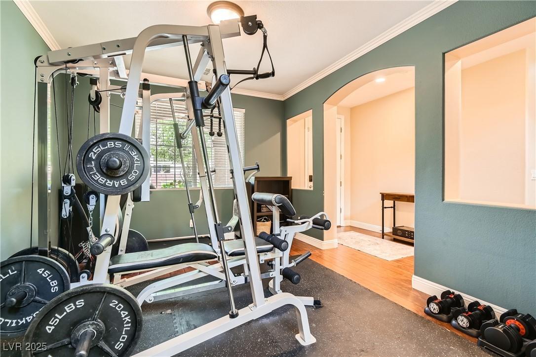 9192 Moose Country Pl, Las Vegas, NV 89178 - exercise area with ornamental molding, arched walkways, baseboards, and wood finished floors