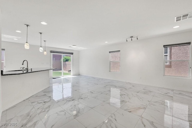 8755 Spanish Ridge Ave, Las Vegas, NV 89148 - unfurnished living room with recessed lighting, light marble finish floors, baseboards, and a sink