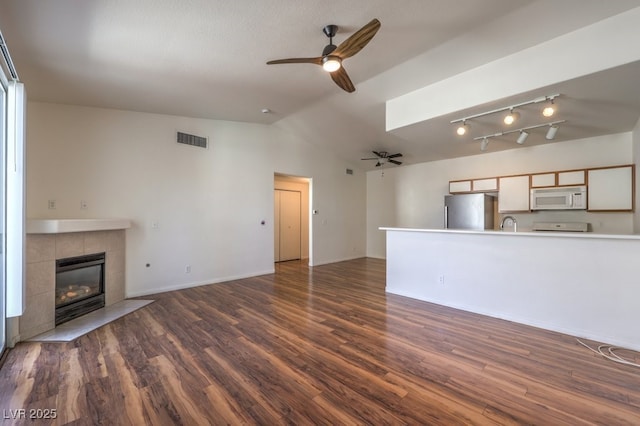 4960 Harrison Dr Unit 214, Las Vegas, NV 89120 - unfurnished living room with ceiling fan, lofted ceiling, dark wood finished floors, a tile fireplace, and baseboards