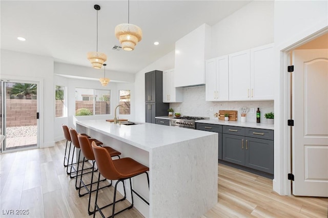 4176 Demoline Cir, Las Vegas, NV 89141 - kitchen featuring gray cabinets, decorative backsplash, an island with sink, a kitchen breakfast bar, and decorative light fixtures