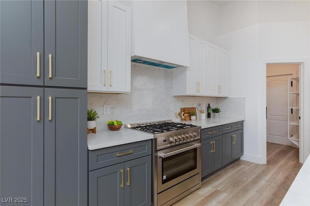 4176 Demoline Cir, Las Vegas, NV 89141 - kitchen with high end range, light countertops, tasteful backsplash, light wood-style flooring, and white cabinets
