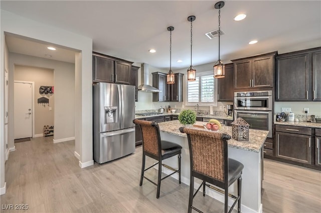 2711 Evolutionary Ln, Las Vegas, NV 89138 - kitchen with stainless steel appliances, wall chimney range hood, dark brown cabinetry, light wood finished floors, and recessed lighting