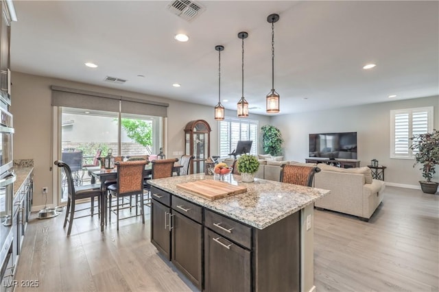 2711 Evolutionary Ln, Las Vegas, NV 89138 - kitchen featuring light wood-style flooring, baseboards, recessed lighting, dark brown cabinets, and a kitchen island
