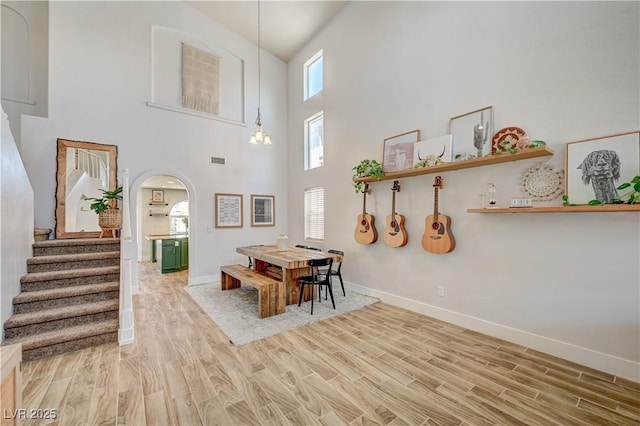 412 Orchid Oasis Ave, North Las Vegas, NV 89031 - dining space featuring arched walkways, wood finished floors, stairway, and a high ceiling