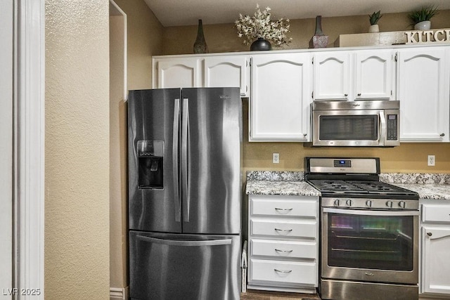 499 Eagle Vista Dr, Henderson, NV 89012 - kitchen featuring appliances with stainless steel finishes, white cabinets, light stone counters, and a textured wall