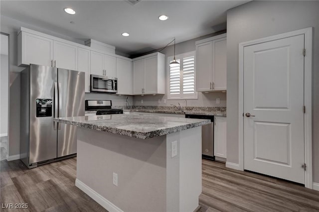 1040 Via Panfilo Ave, Henderson, NV 89011 - kitchen with appliances with stainless steel finishes, wood finished floors, a center island, light stone countertops, and white cabinets